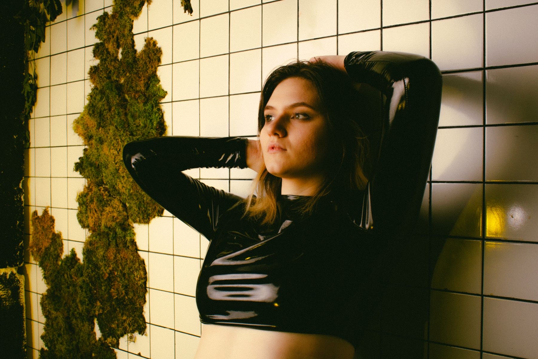 Person in glänzendem schwarzem Latex-Oberteil
